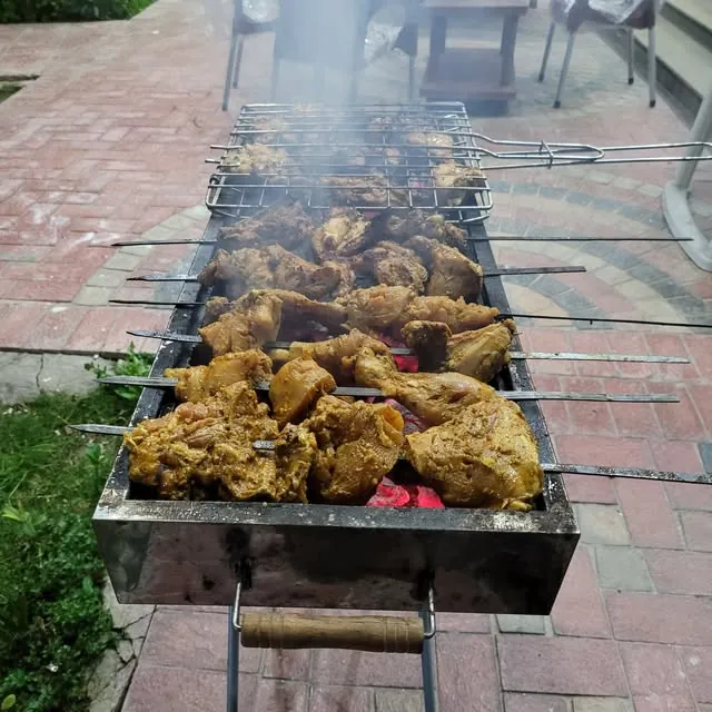 Chicken tikka and kebabs on skewers over the charcoal BBQ grill