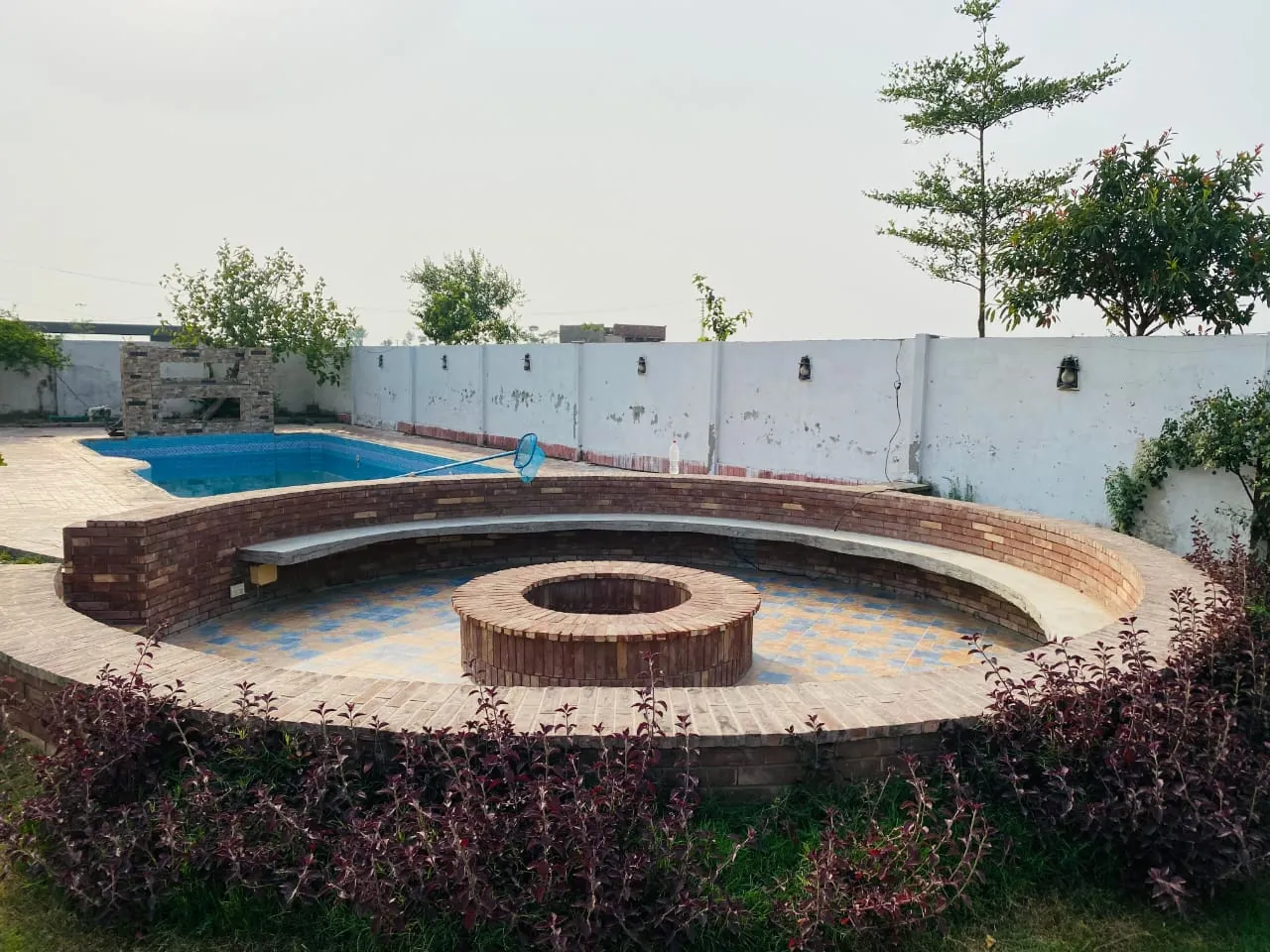 Round brick fire pit with curved bench seating for more than 50 guests beside the pool