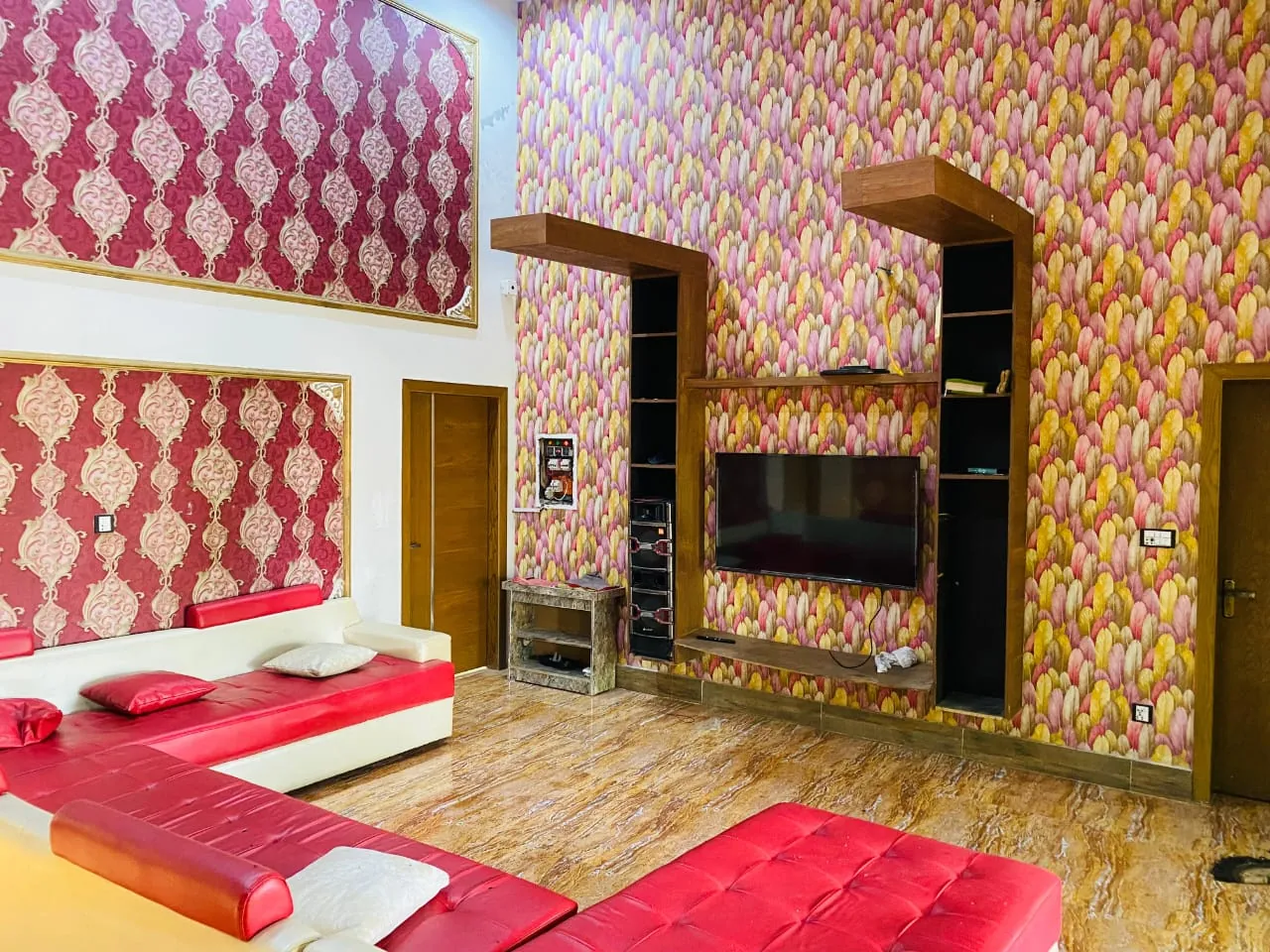 Farmhouse lounge with red sofas, a wall-mounted TV and patterned wallpaper