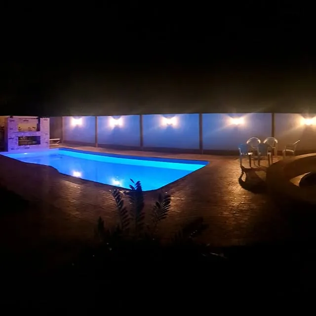 The pool lit by underwater lights after sunset, with poolside seating