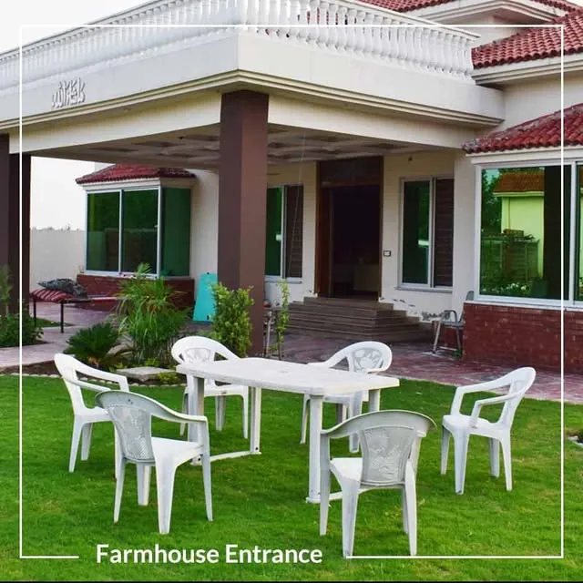 Covered veranda of the farmhouse with garden chairs and a table set on the lawn